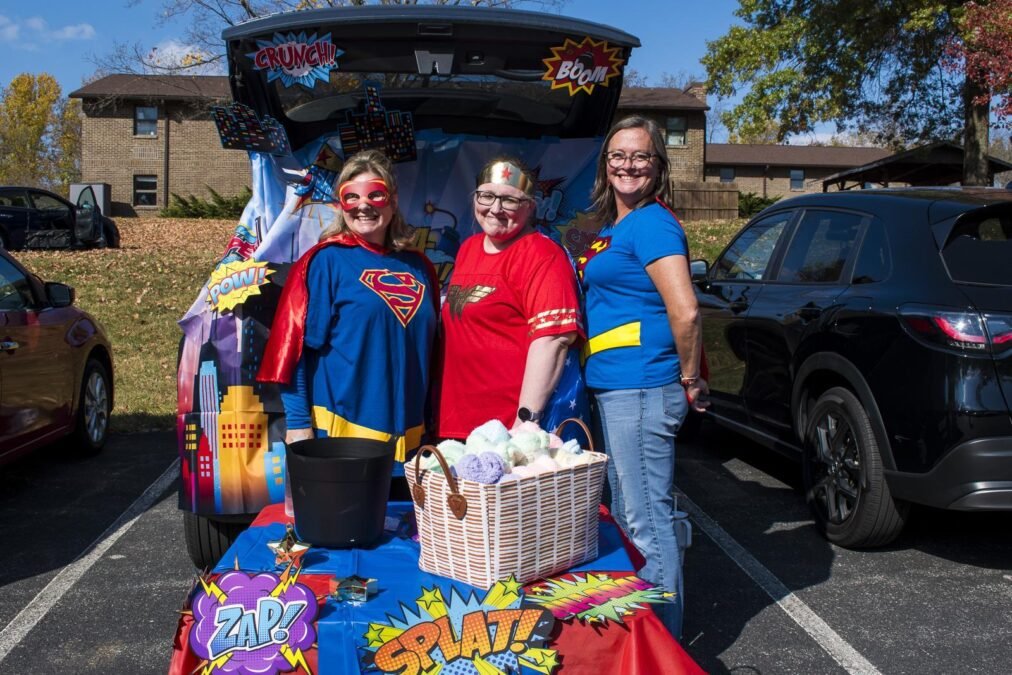 Superhero-themed trunk or treat car with colorful comic decorations and city skyline