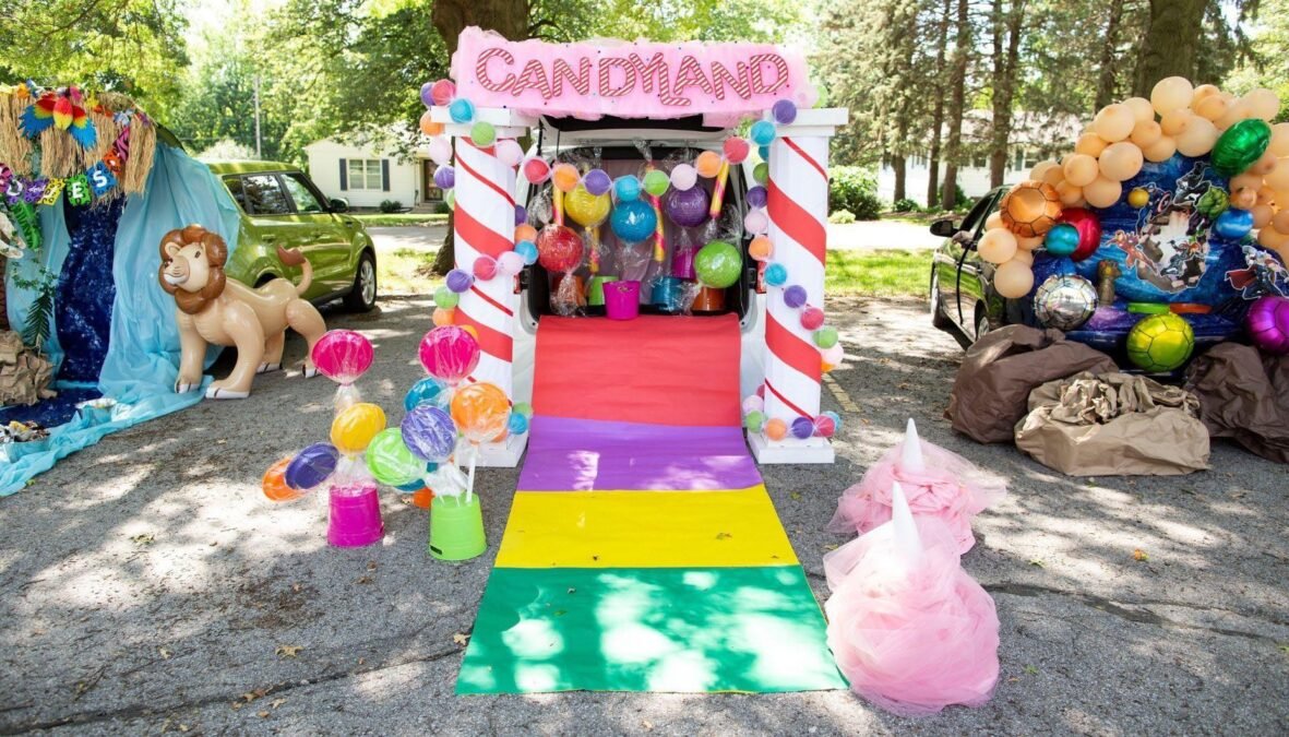 Candy land trunk or treat car with colorful oversized candy decorations and balloons