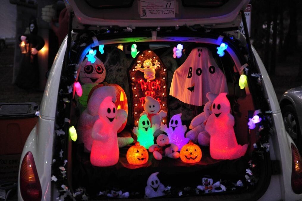 Glow-in-the-dark trunk or treat car with neon Halloween decorations and colorful lights